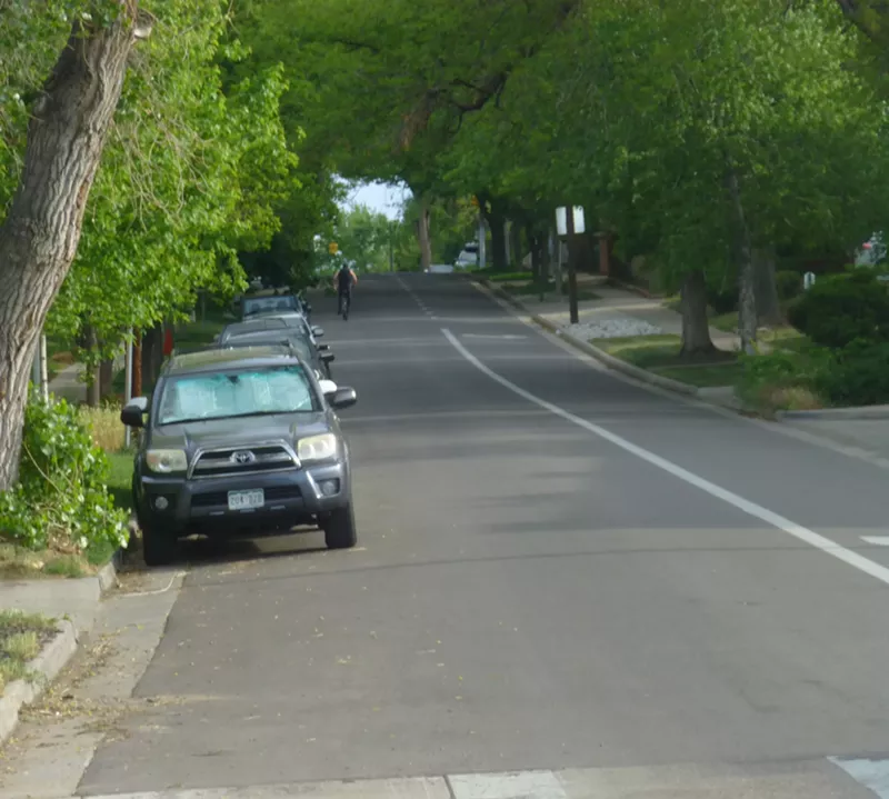 Image: A lone bicylist heads north on the 600 block of Washington Street, where on-street parking has already been halved by a right-turn lane.