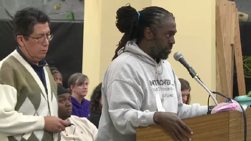 Image: Hashim Coates seen at the podium after being allowed to finish his remarks during a November 14 DPS school board meeting. Board vice president Auon'tai M. Anderson is in the background between Coates and his Spanish-language translator, left.