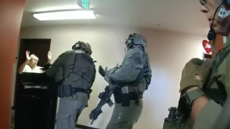 Image: A body-camera image of plaintiff Sharon Shelton-Knight raising her hands as a Denver Police officer points an assault rifle at her chest.