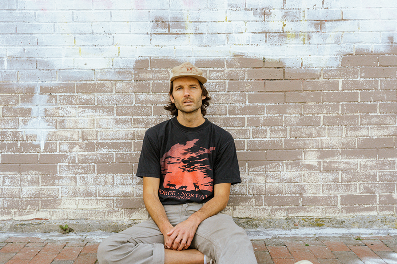 Image: a man sitting down in a yellow hat