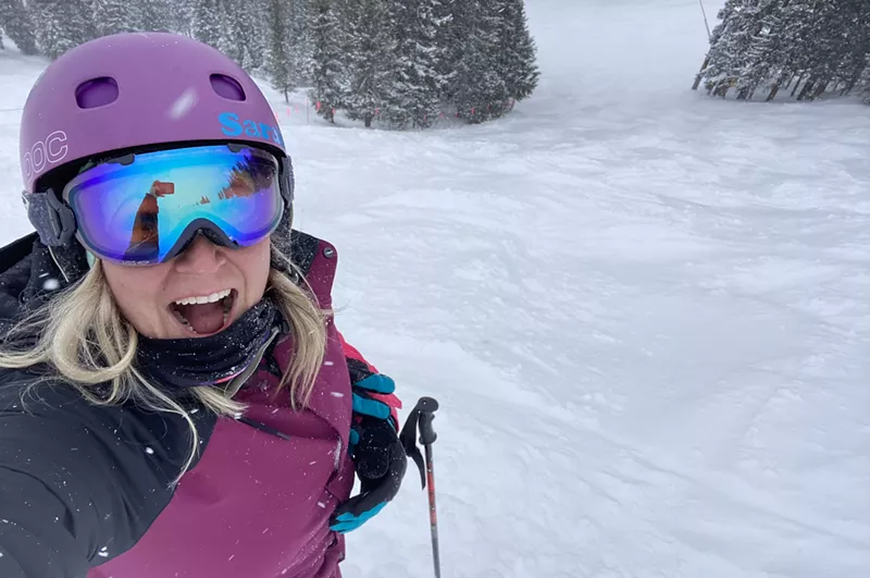 Image: A woman in pink jacket takes selfie while skiing in snow
