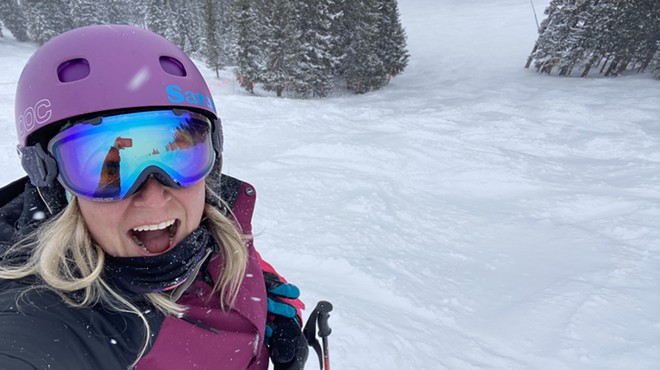 A woman in pink jacket takes selfie while skiing in snow